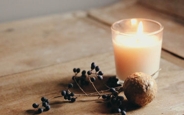 Lit candle on a wooden table next to some dried berries
