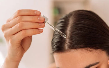 Woman applying oil to her hairline
