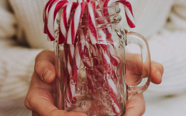 Person holds a cup full of red and white candy canes