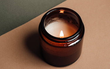 Small lit candle in an amber glass jar