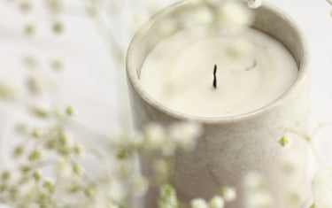 Candle in a pot surrounded by botanicals