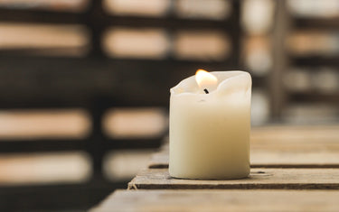 Small lit candle sat on a shelf