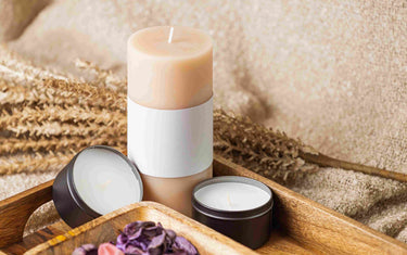 Pillar candle and packaged candles on a tray.