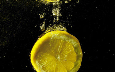 Slice of lemon falling into water.