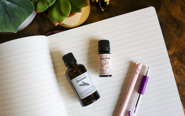 Rosemary and grapefruit essential oils on a notepad.