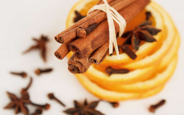 Bundle of Cinnamon sticks and clove on top of sliced orange