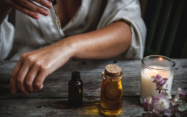 Woman applying oil to her skin with a dropper