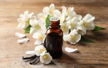 Amber glass bottle of vanilla essential oil with vanilla flowers around it