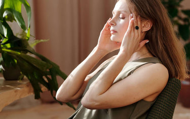 Woman sitting down with hands on head