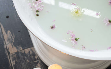 Full bath next to candles and petals. 