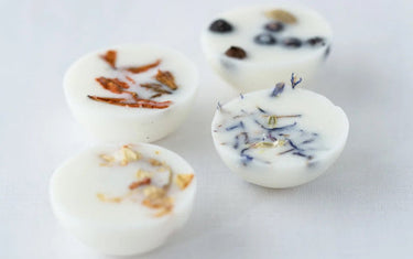 Four wax melts with their own botanicals within each one. One red, one yellow, one purple and one black.