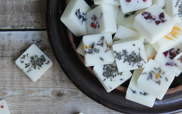 Bowl of square wax melts with an assortment of botanicals sprinkled in