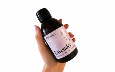 Hand holding a 250ml bottle of our lavender oil for hair and skin against a white background