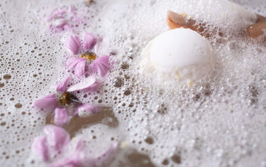 Bath bomb in a foamy bath with petals on