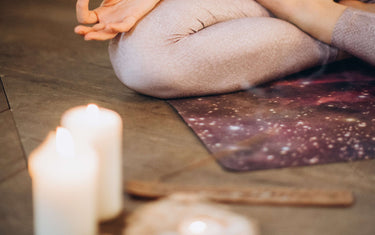 Woman practicing yoga on the floor with lit candles