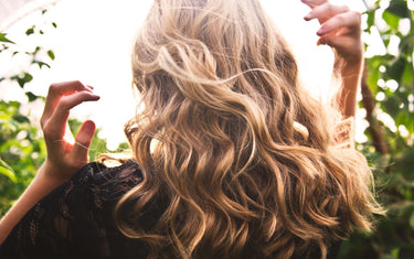 Back of woman with blond curly hair and armed raised