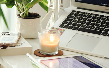 Work from home set up with a laptop, tablet and a lit candle.