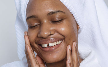 Smiling women in bath robe applies skin tonic