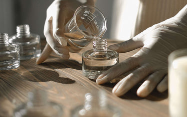 Person pouring fragrance oil into reed diffuser.