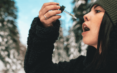 Woman putting dropper up to mouth.