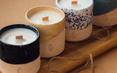 4 candles in a row with wooden wicks and ceramic containers