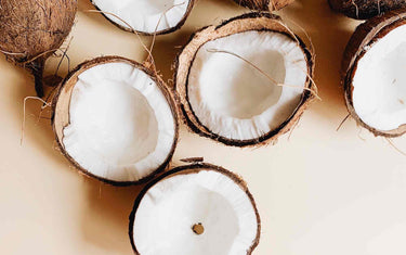 Many opened coconuts on a light brown background