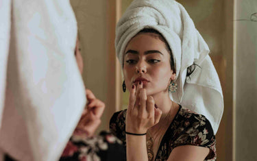 Woman looking at herself in the mirror and touching her face.