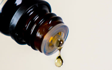 Close up of a dropper bottle with a drop coming out