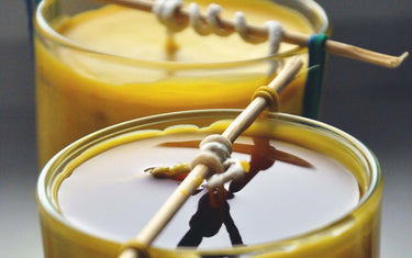 Two yellow candles with the wicks tied up to keep them straight