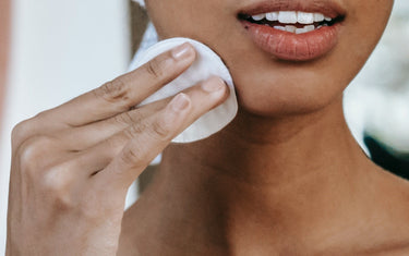 Woman cleaning face with cotton pad