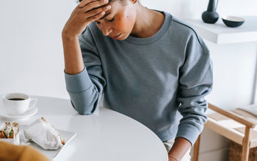 Woman sitting down and holding her head