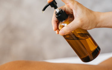 Bottle of carrier oil being applied onto person's back