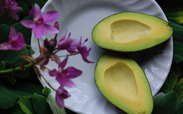 Chopped avocado on a plate next to flowers.