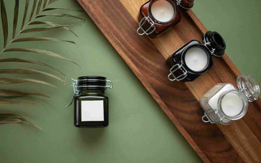 Four jar candles displayed on a green and wooden background.