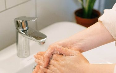 Person washing hands over a bathroom sink.