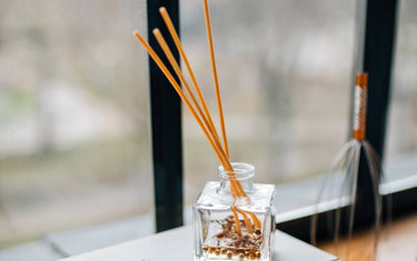 Reed diffuser on a pile of books next to a window