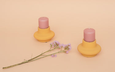 Two pink candles in homemade candle holders with a flower.