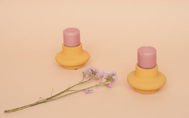 Two pink candles in homemade candle holders with a flower.