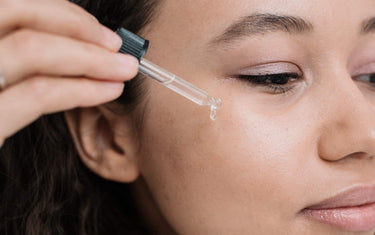 Woman using a dropper to drop diluted rosemary oil onto her skin