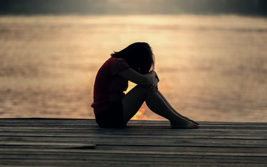 Woman hunched over and holding her legs close