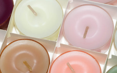 A selection of multi-coloured tea candles in a box