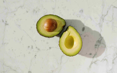 Avocado cut in half on white marble.