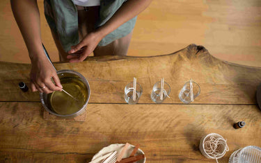 Person making candles on a wooden table. 