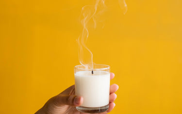 A hand holding a candle with a yellow background