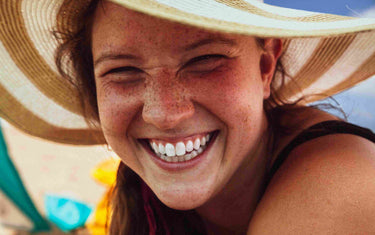 Woman smiling on the beach with white teeth. 