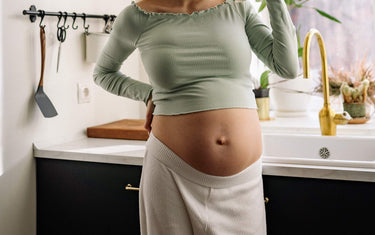 Pregnant lady standing by the sink in her kitchen