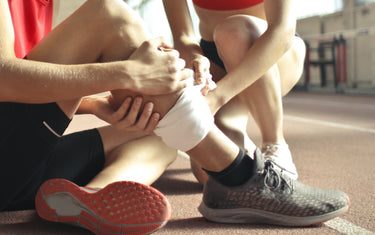 Man holding leg after injury on a running track. 