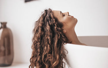 Woman relaxing in the bath with her hair hanging out of the bath