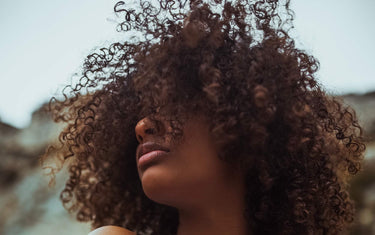 Black woman with natural hair blowing in the wind. Blue sky as a background